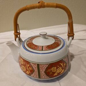 Vintage Japanese ceramic teapot with bamboo handle and floral motifs.
